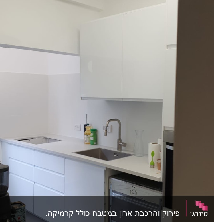 מטבח עם ארונות לבנים, כיור וברז מותקנים
